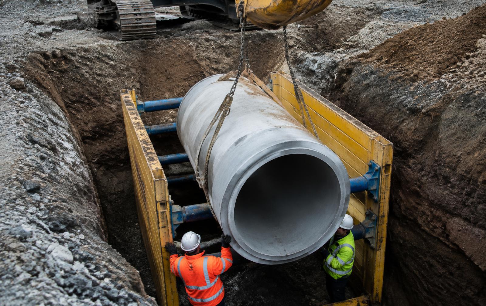 Concrete storm pipe lowered into a shored trench