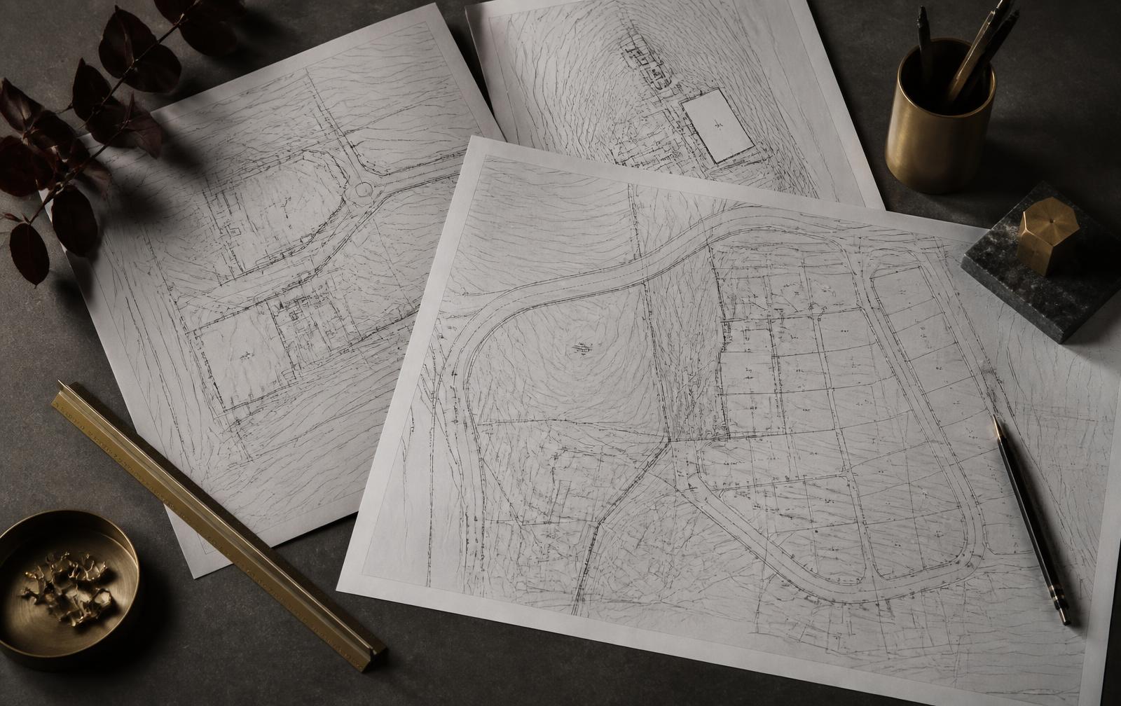 Civil engineering site plans and plat drawings laid out on a dark table